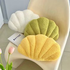 three bath towels sitting on top of a white chair next to a pink tulip