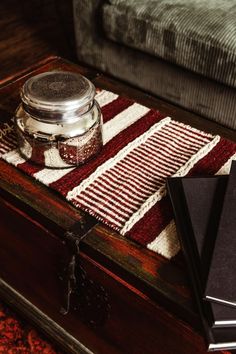 a wooden table topped with a jar of jam on top of a red and white rug