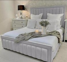 a bed with white linens and pillows in a bedroom setting, next to a night stand