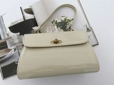 Listed from my own private collection, is this sophisticated 1950s patent plastic box style handbag. Colour is cream. Overall, this bag is in very good condition for age. The bag also includes a shoulder strap that can be attached to the body of the bag (handle). The exterior of the bag is very good with only minor tarnishing to lock of bag and metal side frames. The exterior of bag is good, with some staining at the base of the bag, but due to age this does not distract from overall piece. Has inside zipper pocket which works effectively. Shoulder strap is in very good condition. Bag measures 21.5cm x 16cm (does not include the handle). This is truly a very special piece. Made in NSW, Australia. Circa 1950s. Cream Handbag, Gold Evening Bag, Pearl Necklace Vintage, Top Handle Bags, Nsw Australia, Vintage Pearls, Bag Handle, Vintage 1950s, Evening Bags