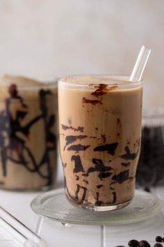 two glasses filled with ice cream sitting on top of a white counter next to coffee beans