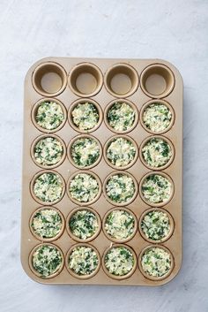 cupcakes with spinach and cheese in muffin tins on a white surface