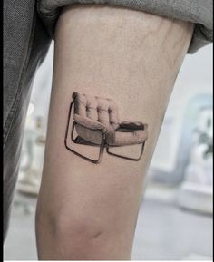 a tattoo on the leg of a person with a chair in front of them,