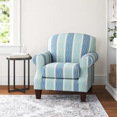 a blue and white striped chair sitting on top of a rug next to a table