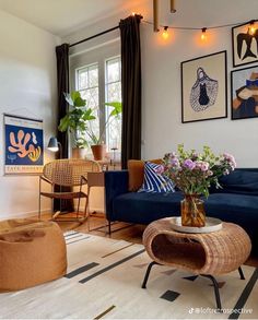 a living room with blue couches and pictures on the wall above them, along with chairs