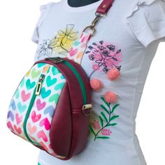 a women's handbag with flowers and hearts on the front, attached to a mannequin torso