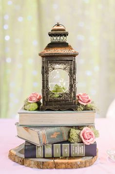 there is a small clock on top of two books and flowers in front of it