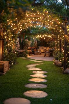 a pathway made out of stepping stones is lit up with fairy lights and surrounded by greenery