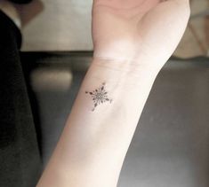 a woman's wrist with a small flower tattoo on the left side of her arm