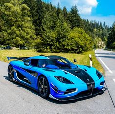 a blue and black sports car driving down the road