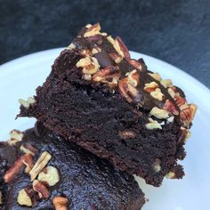 two pieces of chocolate cake sitting on top of a white plate next to each other