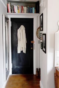 a black door with bookshelves and pictures on the wall