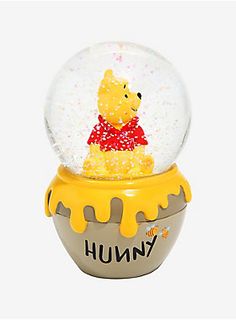 a snow globe with a winnie the pooh character in it's center, on top of a yellow base