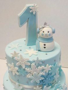 a blue frosted cake with snowflakes and a number one on top