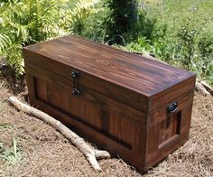 a large wooden box sitting in the middle of some grass and dirt next to trees