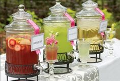 four different types of drinks are on display in glass jars with labels attached to them