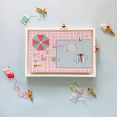 there is a cross stitch pattern on the wall with little toy figures around it and an umbrella