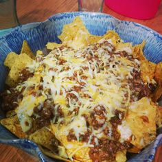 a bowl filled with nachos covered in cheese and chili