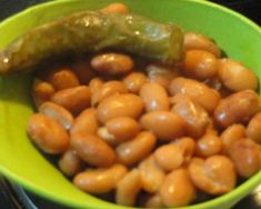 a green bowl filled with beans and a pickle