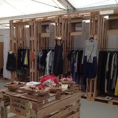 the inside of a clothing store with wooden crates and clothes hanging on racks in front of it