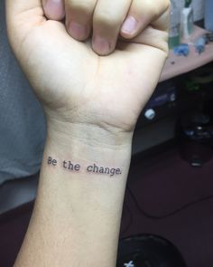 a person with a wrist tattoo that says be the change