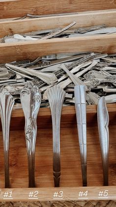 six silver spoons are lined up in a wooden box