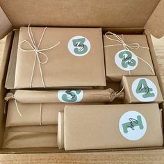 four brown boxes wrapped in brown paper with green and white stickers on the top