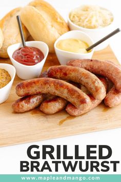 grilled bratwurst on a cutting board with dipping sauces and bread in the background