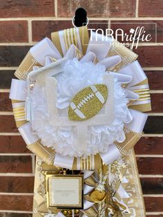 a football themed wreath with gold and white ribbons