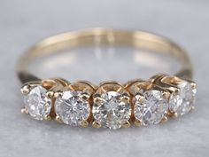 This wedding band features a row of bright and sparkling diamonds, each set into protective four-prong settings. Crafted of 14 karat yellow gold, this ring is a classic design that will be timeless for years to come. Metal: 14K Yellow Gold Gem: 5 Diamonds totaling 1.00 Carat, H in Color, SI2 in ClarityGem Measurements: 4.0 mm, Round Ring Size: 8 Marks: “14K” Stamped on the inside band Wedding Band Yellow Gold, Yellow Gold Diamond Wedding Band, Stacked Diamond Bands, Jewels Diy, Jewelry Stacking, Australian Sapphire, Gold Diamond Band, Unusual Rings, Ladies Diamond Rings