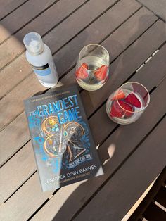 a book sitting on top of a wooden table next to two glasses filled with liquid