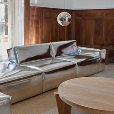 a living room filled with furniture next to a wooden table and wall mounted light fixture