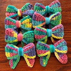 several crocheted bows are arranged on a wooden surface, one is multicolored