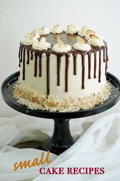 a cake with white frosting and chocolate drizzled on top sitting on a black plate