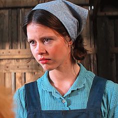 a woman in an apron and hat looking at the camera