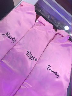 three pink shirts with names on them sitting next to each other