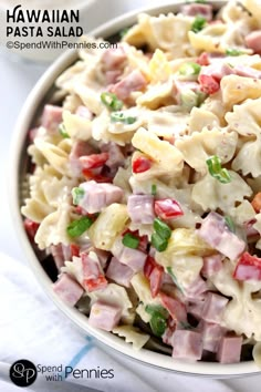 pasta salad with ham and green onions in a bowl on a white tablecloth, ready to be eaten