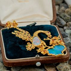 This stunning pendant features a bird and flower design, bezel set with two (2) opal cabochons. The flowers are each four-prong set with one (1) round mixed cut hessonite garnet. The eye of the bird is flush set with one (1) round mixed cut ruby. The feathers of the bird are flush set with a total of twenty- five (25) round mixed cut tourmaline and seventeen (17) round mixed cut demantoid garnets. The pendant measures 90.0mm long, including the bail and 40.0mm wide. The chain in the photo is not Elegant Multi-stone Opal Jewelry, Luxury Hallmarked Opal Jewelry, Luxury Opal Cabochon Jewelry, Opal Jewelry With Gemstone Accents For Formal Occasions, Formal Opal Jewelry With Gemstone Accents, Exquisite Collectible Jewelry Brooch, Exquisite Collectible Brooch Jewelry, Bird And Flower, Gemstone List