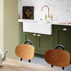 two wooden chairs sitting in front of a kitchen sink and counter top next to a tea kettle