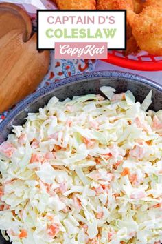 a bowl filled with coleslaw on top of a table next to other foods