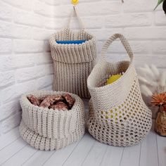 three knitted baskets sitting next to each other on a white tablecloth covered floor