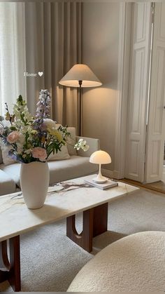 a living room filled with furniture and flowers on top of a table in front of a window