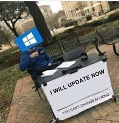 a man sitting at a table with a sign on it that says, i will update now you can't change my mind