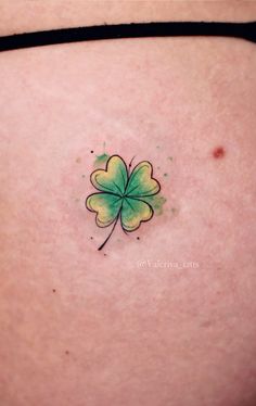 a four leaf clover tattoo on the back of a woman's stomach