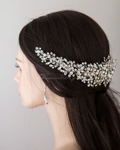 a woman wearing a bridal headpiece with crystal stones and pearls on the side