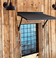 two black lights are hanging from the side of a wooden wall next to a window