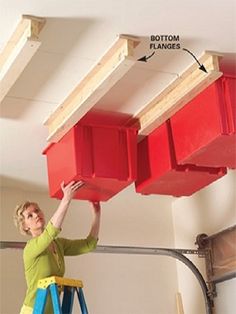 a woman standing on a step ladder holding two red bins above her head, with the bottom planks removed