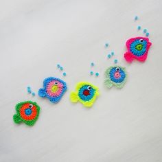 three crocheted fish sitting next to each other on a white surface with beads