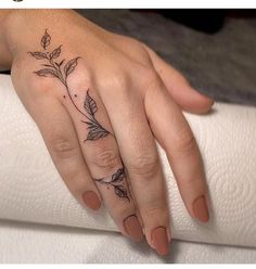 a woman's hand with a flower tattoo on her left thumb and ring finger