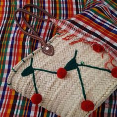 a woven bag with red pom - poms on it